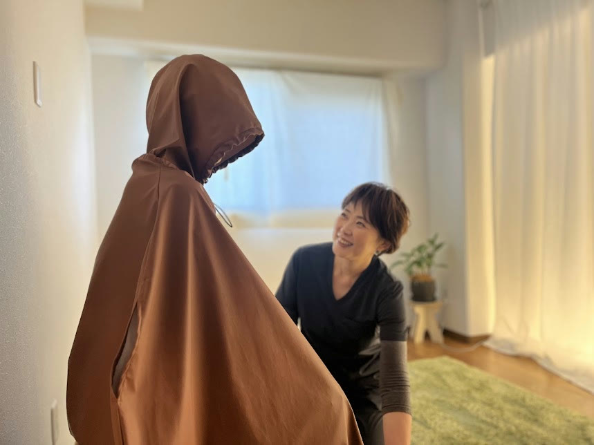 よもぎ蒸しのマントを着たお客様と、笑顔で話す鳥嶋里美